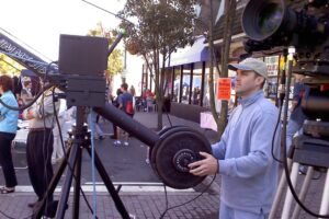 Chris is outdoors behind the controls, operating a camera jib during a live event.